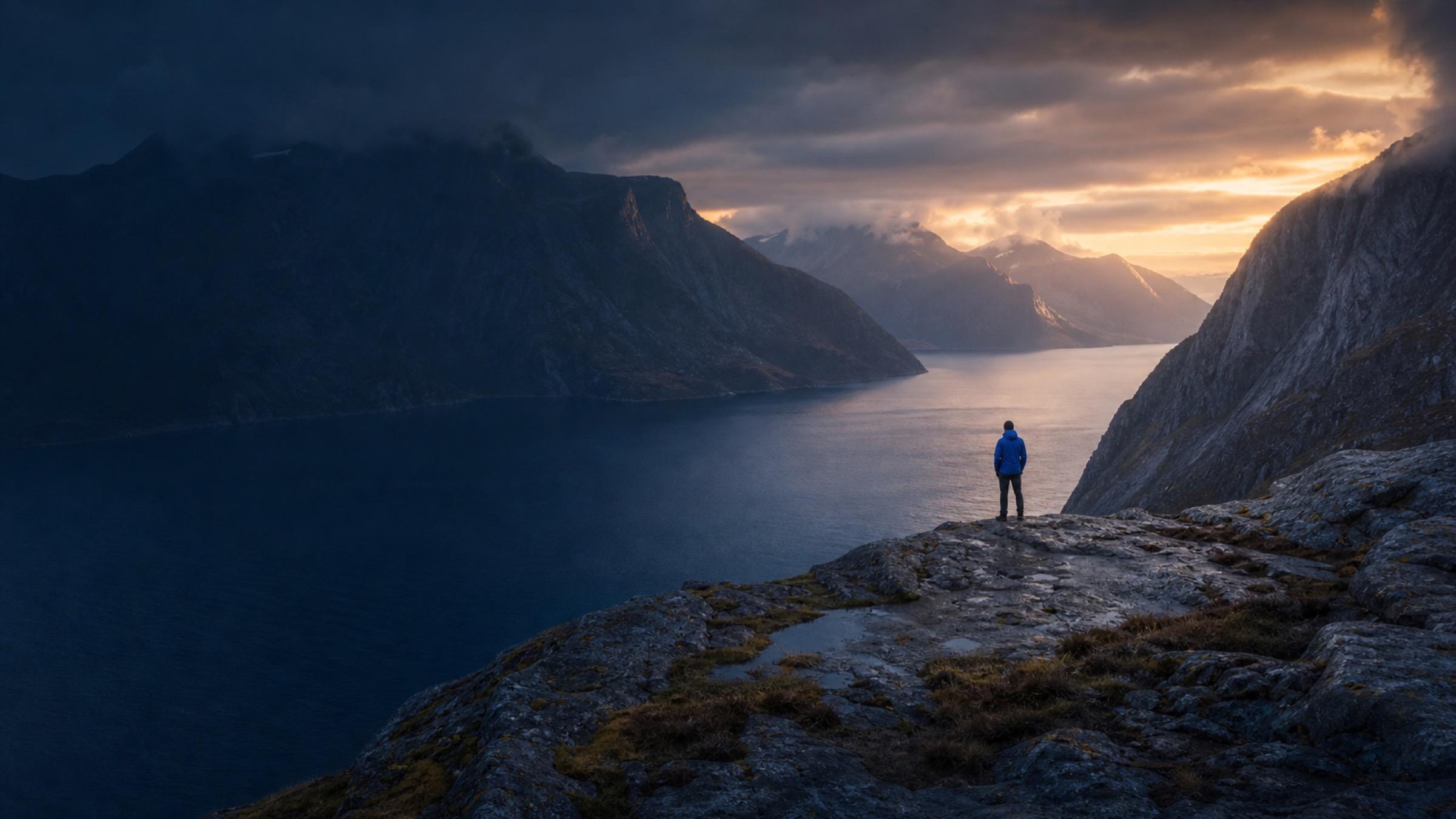 A traveler overlooking a mountain fjord at sunrise.